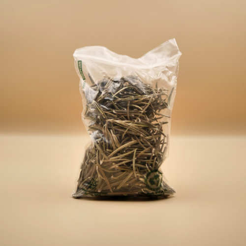 Clear plastic bag filled with dried herbs on a beige background