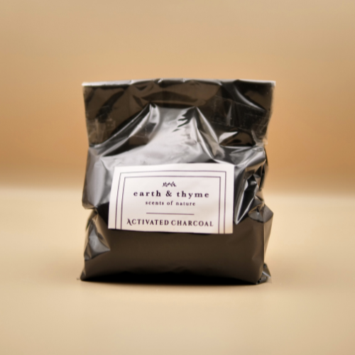 Bag of activated charcoal with 'earth & thyme' label on a beige background